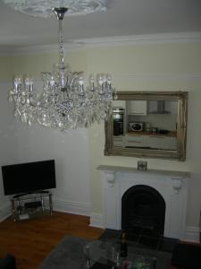 a living room with a chandelier and a mirror at High Street Suites 3 in Ventnor
