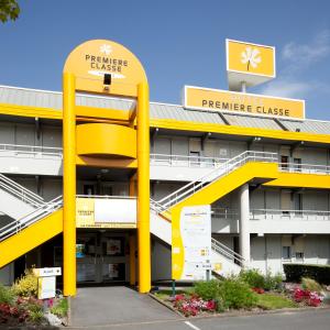 a building with yellow columns in a parking lot at Premiere Classe Quimper in Quimper
