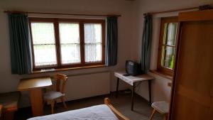 a room with a bed and a tv and two windows at Gasthof Hotel IFENBLICK in Sibratsgfäll