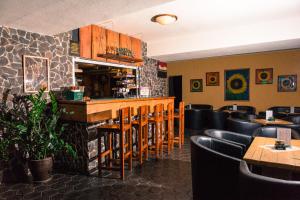 a restaurant with a bar with black chairs and tables at Hotel Liptov in Demanovska Dolina +32 photos