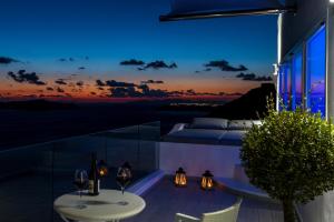 a view from a balcony at night with wine glasses at Fira Deep Blue Suites in Fira