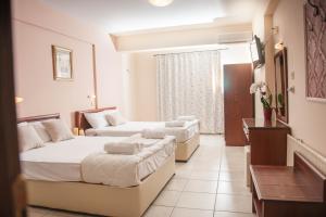 a hotel room with two beds and a window at Hotel Vizantio in Paralia Katerinis