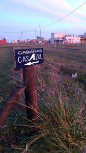 un cartel en un poste de madera en un campo en Cabañas Casazul en Santa Clara del Mar