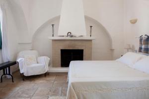 a bedroom with a fireplace and a bed and a chair at Masseria Il Frantoio in Ostuni