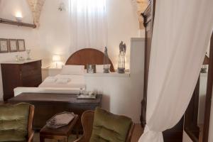 a bedroom with a bed and a desk and chairs at Masseria Il Frantoio in Ostuni