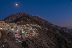 un pueblo al lado de una montaña por la noche en Aphrodite Hotel en Olympos