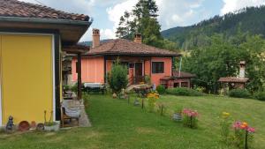 a house with a yard with flowers in front of it at Mechta Guest House in Koprivshtitsa