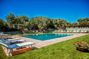 a swimming pool with lounge chairs in a yard at Masseria Il Frantoio in Ostuni