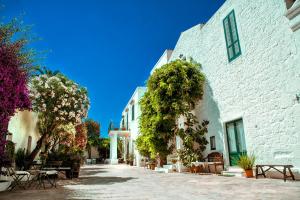 a courtyard of a white building with tables and trees at Masseria Il Frantoio in Ostuni