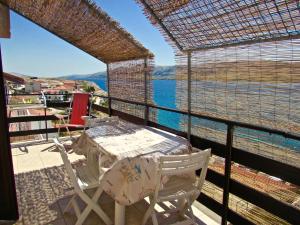 een tafel en stoelen op een balkon met uitzicht op het water bij Apartments Dražica 4 in Zubovići