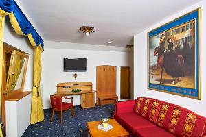 a living room with a red couch and a desk at Landhotel Wiesbauer in Füssen