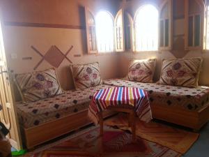 a couch in a room with two windows at Auberge Des Jardins du Dades in Boumalne