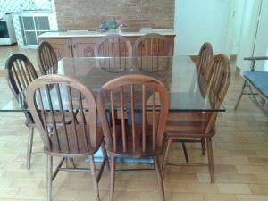 ein Glastisch mit vier Holzstühlen um ihn herum in der Unterkunft Casa em Caraguatatuba in Caraguatatuba