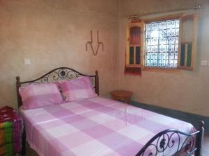 a bedroom with a pink and white bed with a window at Auberge Des Jardins du Dades in Boumalne