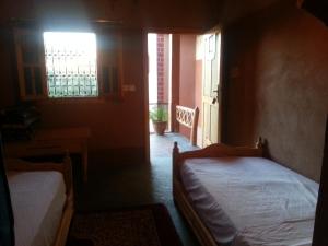 a bedroom with two beds and a window at Auberge Des Jardins du Dades in Boumalne