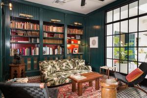 American Trade Hotel في مدينة باناما: غرفة معيشة بجدران خضراء وأريكة وأرفف كتب