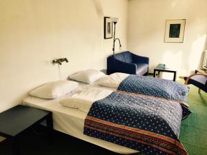 a bedroom with two beds and a blue chair at Sødorp Gjestgivergård Motell in Vinstra