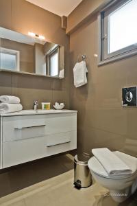 a bathroom with a sink and a toilet and a mirror at Nereus Luxurious Suites in Karpathos Town