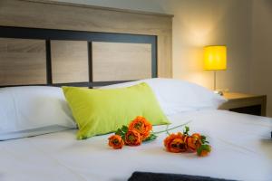 トレモリノスにあるHolidays2Torremolinos Apartamento de 3 dormitorios con terraza y piscina comunitariaのベッドの上に2本の花が飾られています