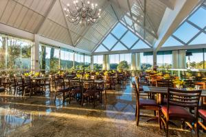 a dining room with tables and chairs and a chandelier at Hotel Dan Inn Campos do Jordão in Campos do Jordão