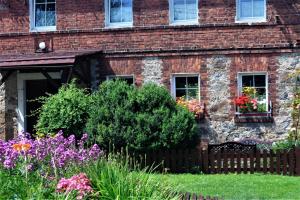 a brick house with flowers in front of it at Gospodarstwo Agroturystyczne Powierzówka in Leśna
