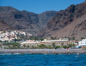 a beach with a bunch of people on it with mountains at Hotel Gran Rey in Valle Gran Rey