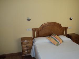 Apartamentos Casa Rosendo في كانجاس ديل نارسيا: غرفة نوم مع سرير مع اللوح الأمامي الخشبي ومداخلات ليلية