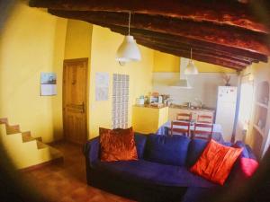 a living room with a blue couch and a kitchen at Casa Rural FuenteVieja in La Mata de los Olmos