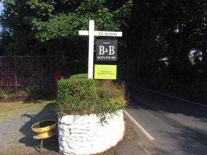 a white cross with a sign on a street at Ty Mawr at Bethania B&B in Llanon