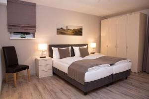 a bedroom with a large bed and a chair at Appartements am Aquarium in Helgoland