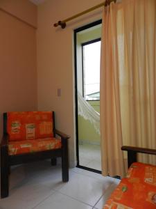 Habitación con silla y puerta corredera de cristal en Aparthotel Eporedia en Natal