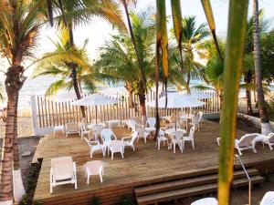 una terraza de madera con sillas y sombrillas en la playa en Cabañas Aqua Blue en Coveñas