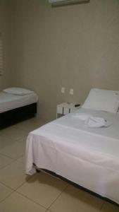 a bedroom with two beds with white sheets at Hotel Boiadeiro in Araguaína