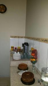 um balcão de cozinha com dois bolos e uma taça de fruta em Hotel Boiadeiro em Araguaína