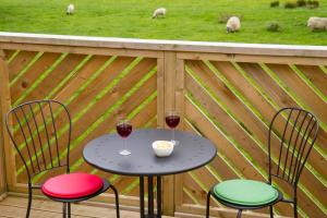 a table with two glasses of wine on a deck with sheep at Badgers Den in Linlithgow
