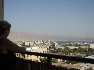 uma mulher de pé numa varanda com vista para uma cidade em ERA home boutique em Eilat