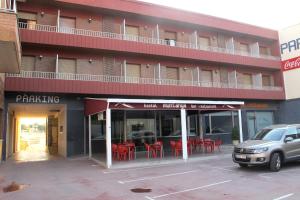 Artesa de Segre的住宿－Hostal Muntanya，大楼前的停车场,配有红色椅子