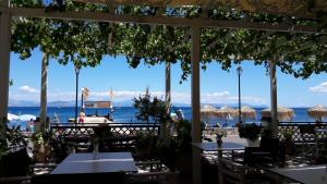 a view of the ocean from a restaurant with tables and umbrellas at Eros Beach Hotel in Benitses