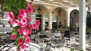 a restaurant with tables and chairs and pink flowers at Eros Beach Hotel in Benitses