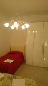 a bedroom with a red bed and a chandelier at Appartamento Giulia in Moneglia