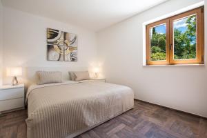 a white bedroom with a bed and a window at Apartments Villa Diamant with Pool & Whirlpool in Čižići +31 photos