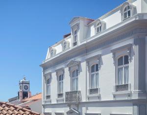 un edificio blanco con una torre de reloj encima en AC-Armazéns Cogumbreiro, en Ponta Delgada