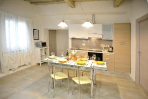 Una cocina con mesa y sillas y una cocina con gabinetes blancos. en Ognissanti 67, en Florencia