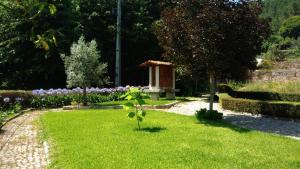 a garden with a small bird house in the grass at THE RIVER HOUSE - Termas Guesthouse in Termas de Sao Pedro do Sul