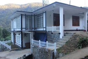 a small white house with a fence in front of it at Believe Inn in Nuwara Eliya