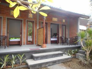 een huis met een veranda met stoelen en tafels bij Pondok Indah Homestay in Sidemen