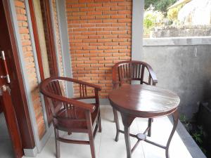deux chaises et une table en bois sur un porche dans l'établissement Pondok Indah Homestay, à Sidemen