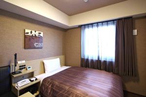 a hotel room with a bed and a window at Hotel Route-Inn Sabae -Kokudou 8 Gou- in Sabae