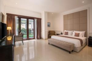 a large bedroom with a large bed and a couch at Grand Palace Hotel Sanur - Bali in Sanur