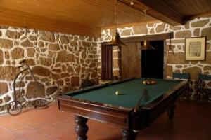 a pool table in a room with a stone wall at Agro-Turismo - Quinta do Pinheiro in Cavadoude